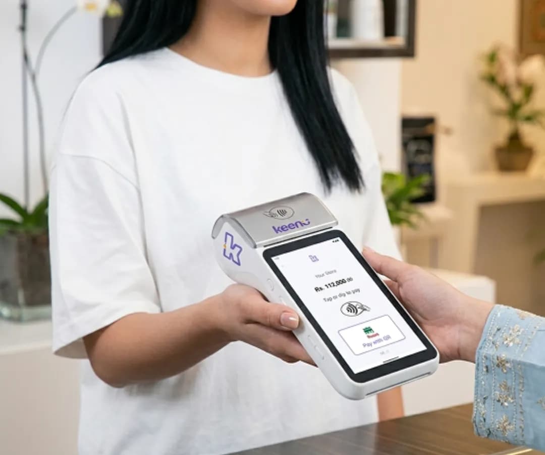 Returning client tapping a card to pay on a Keenu terminal at a beauty salon
