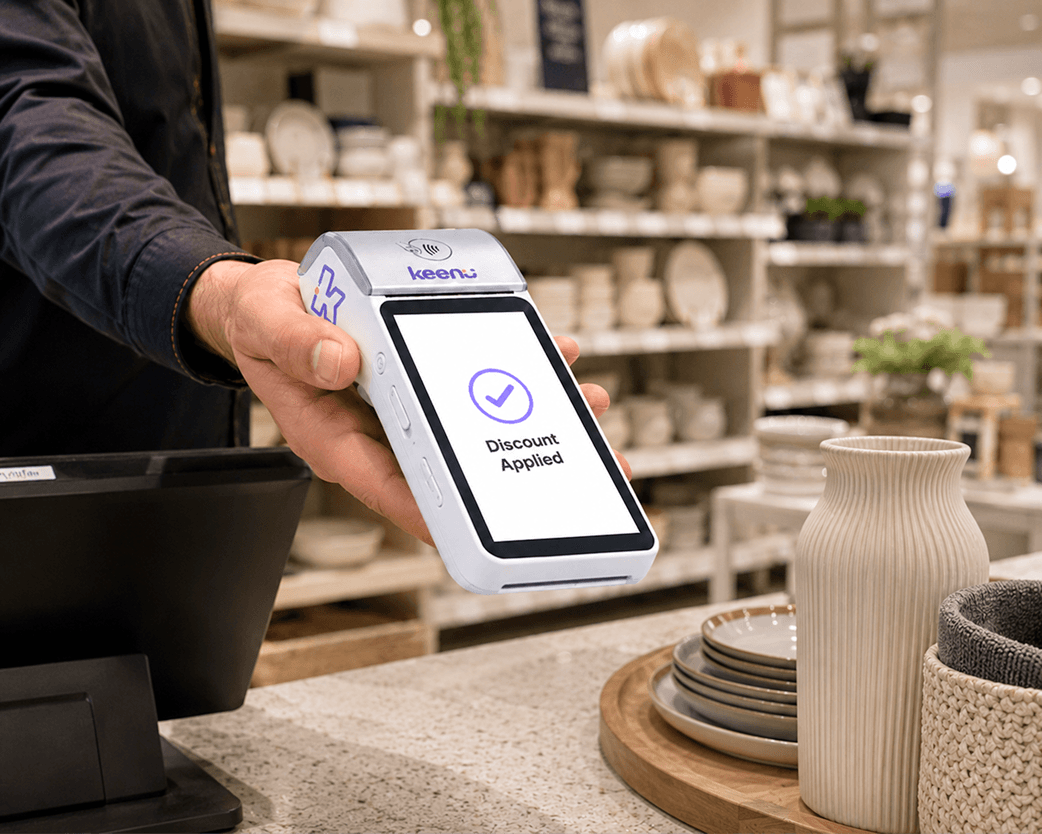 Customer tapping a card on a Keenu terminal that applies a discount at a retail counter