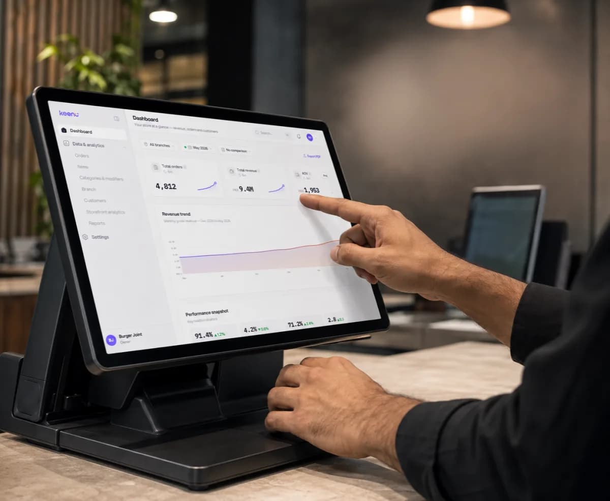Cashier loading receipt paper into a Keenu point-of-sale terminal